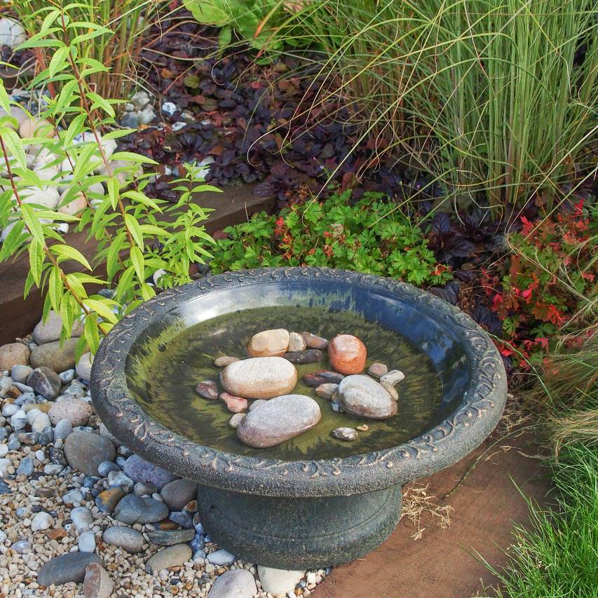 Coniston bird bath standing on pebbles