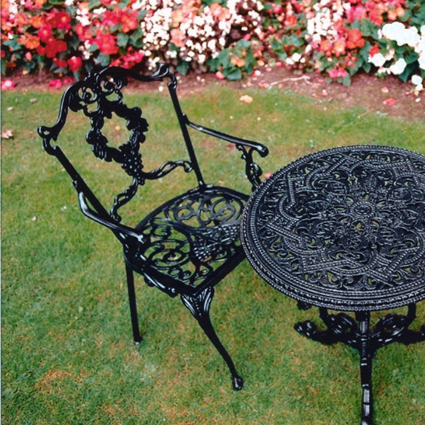 Jardine Leisure Grape carver chair with Grape round table in satin black finish standing on lawn next to flowerbed