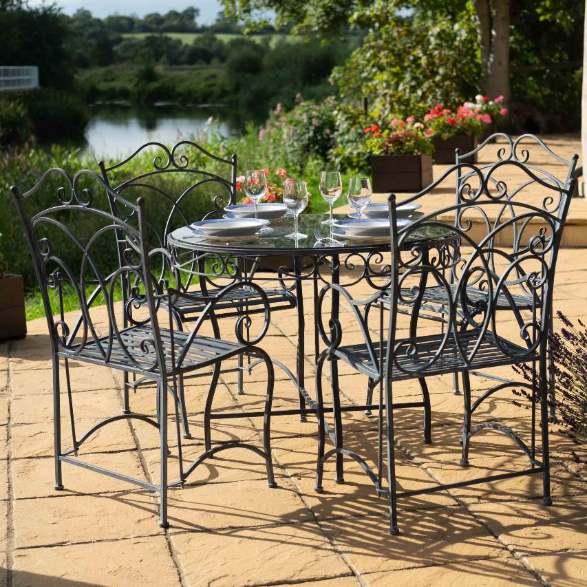 Heritage 5-piece bistro set in dark lead on a patio, with the table set with wine glasses and plates, overlooking a river in the background.