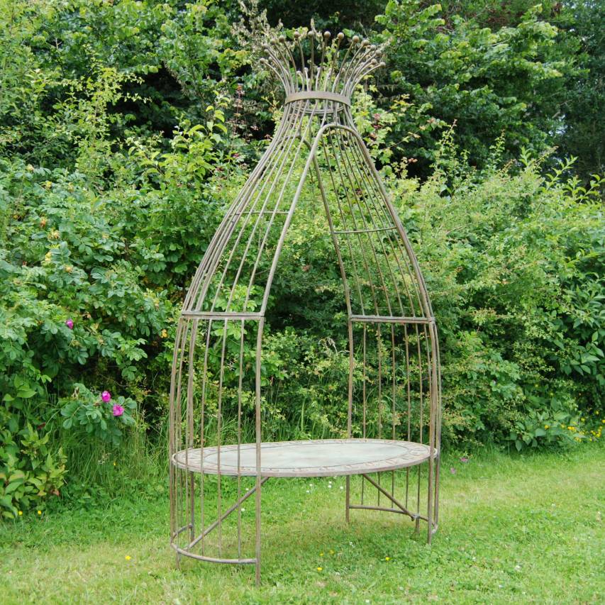 Wigwam arbour standing on grass in front of hedge with pink roses